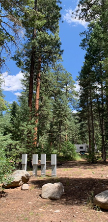 Four Milbank pedestals stand in the trees with an RV half-hidden in the background.