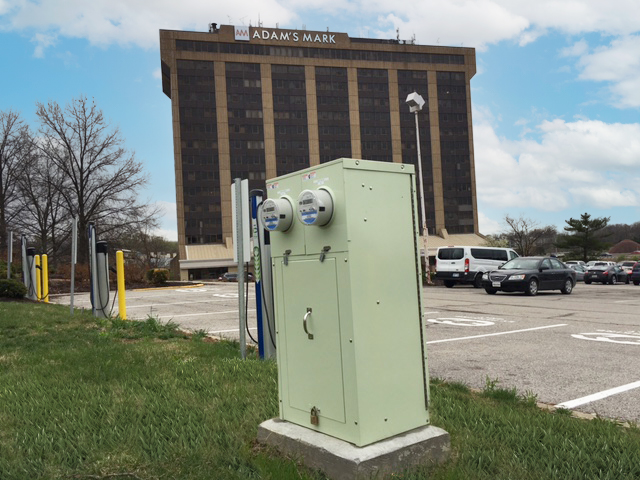 A green Milbank enclosed control provides power distribution for a nearby EV charger.