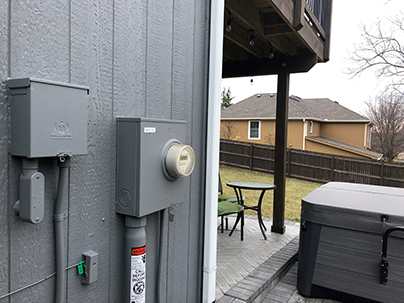 Milbank hot tub disconnect and meter socket mounted on wall by hot tub.