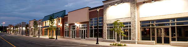 The exterior of a ship malls with shop fronts lit up by street lights.