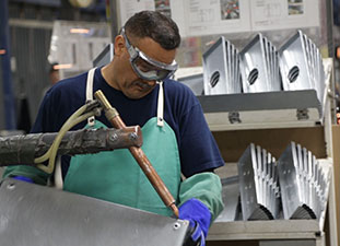 A Milbank plant employee welds the corner of an enclosure.