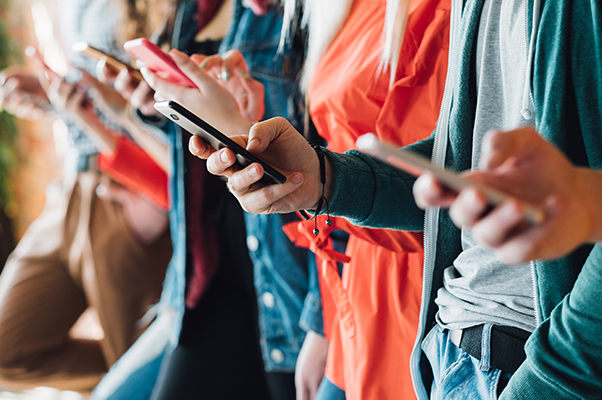 A row of people all using cell phones and smart devices.